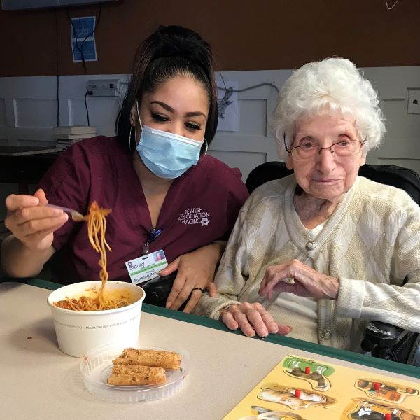 Caregiver helping senior eat noodles