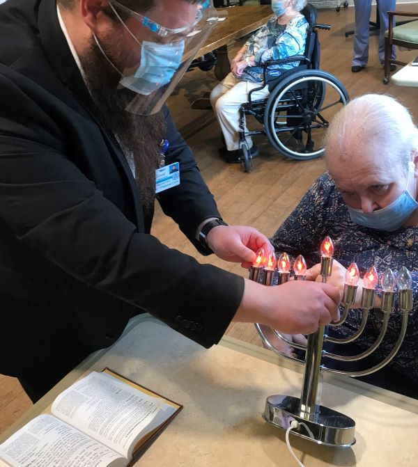 Senior and caregiver lighting a menorah