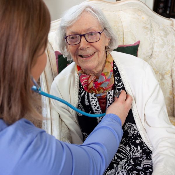 Caregiver listening to a senior woman's heart with a stethoscope