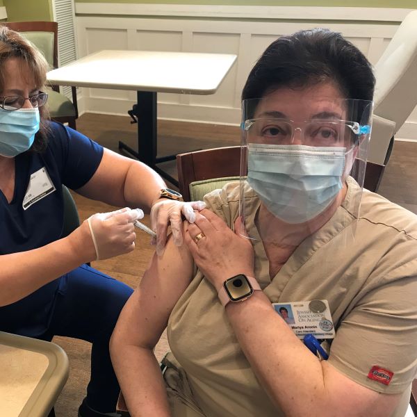Staff member Mariya receiving a vaccine