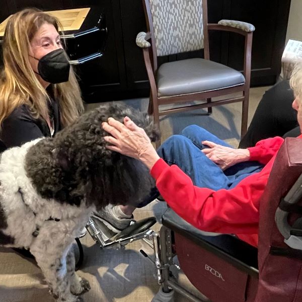 Senior Helen Schugar pets a dog in a wheelchair