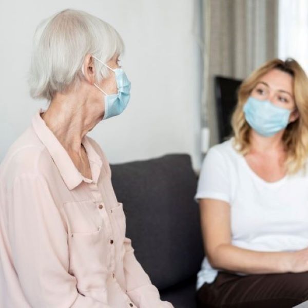 Senior woman and her caregiver wearing COVID-19 masks